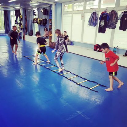 A group of children are playing with a ladder in a gym