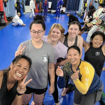 A group of women are posing for a picture in a gym.