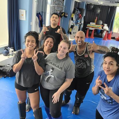 A group of people are posing for a picture in a gym.