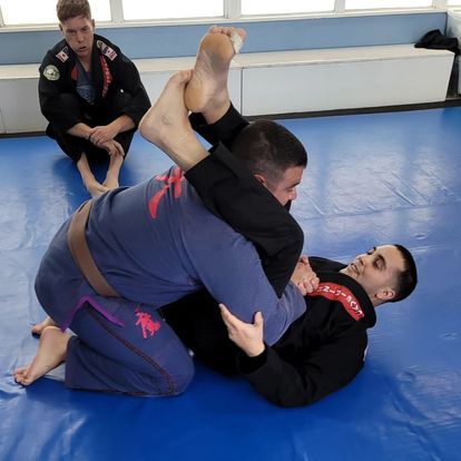 Two men are practicing martial arts on a blue mat