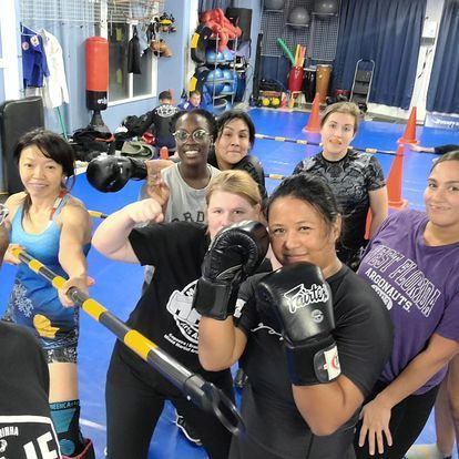 A group of women wearing boxing gloves are posing for a picture