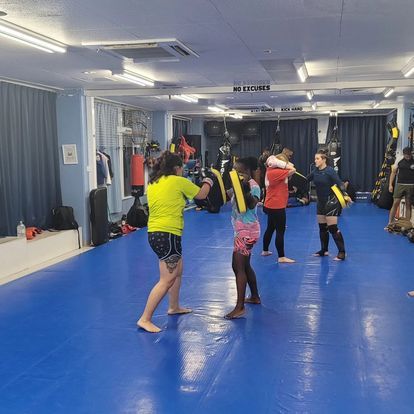 A group of people are standing on a blue mat in a gym.
