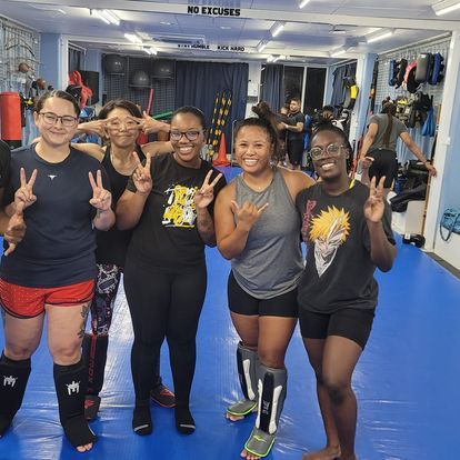A group of women are posing for a picture in a gym.