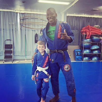 A man and a boy are posing for a picture in a gym