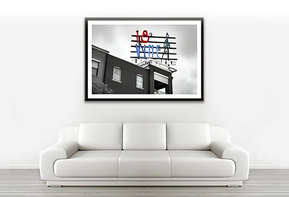 White couch below a framed photograph of a partially colored vintage sign.