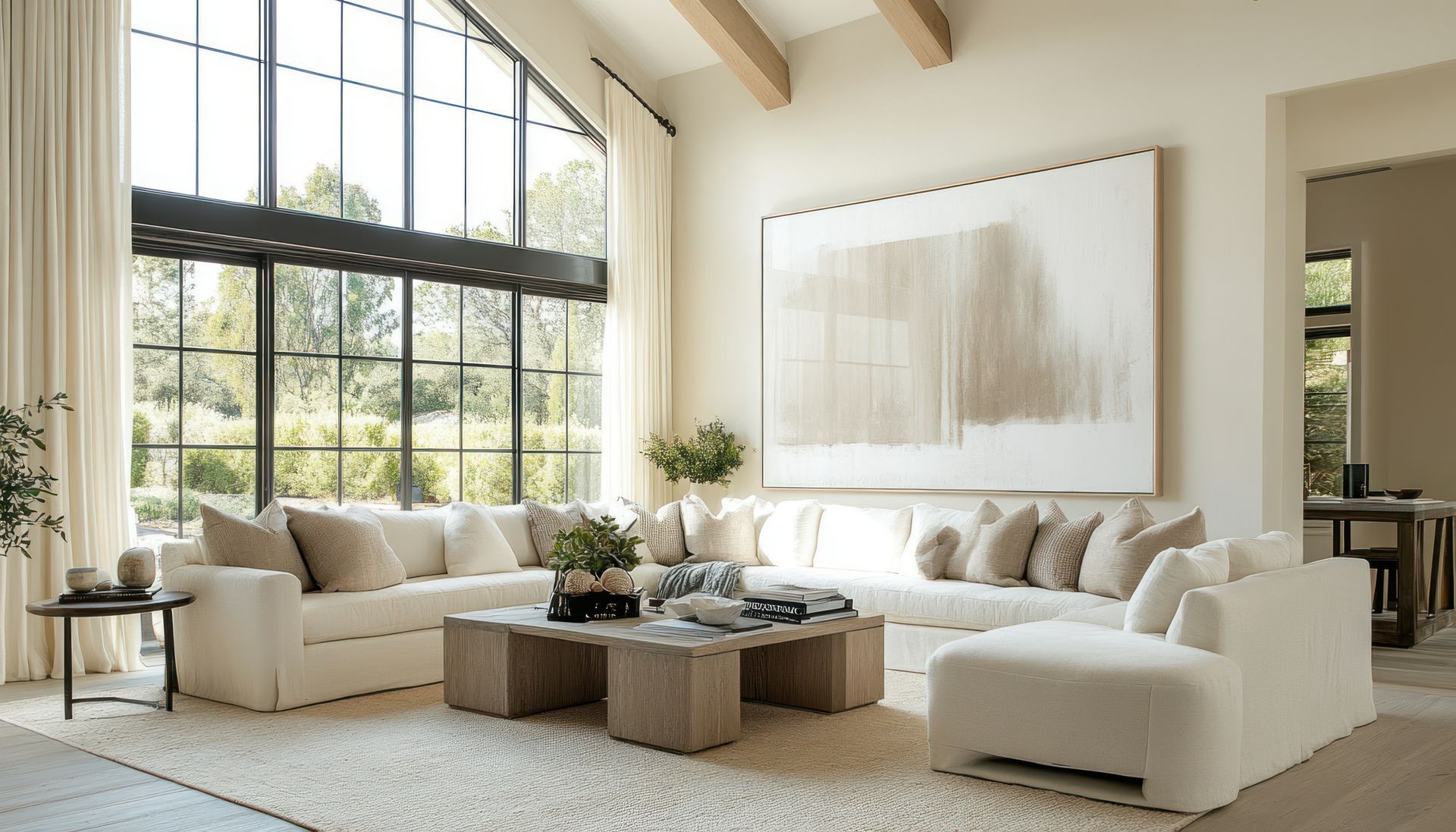 Salon spacieux avec de grandes fenêtres, un canapé sectionnel blanc, de l'art abstrait et une table basse en bois.