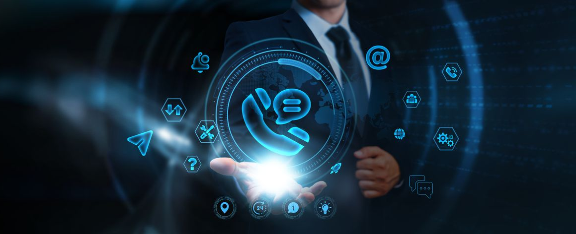 A person in a suit holding a glowing digital phone icon with various technological symbols around it.