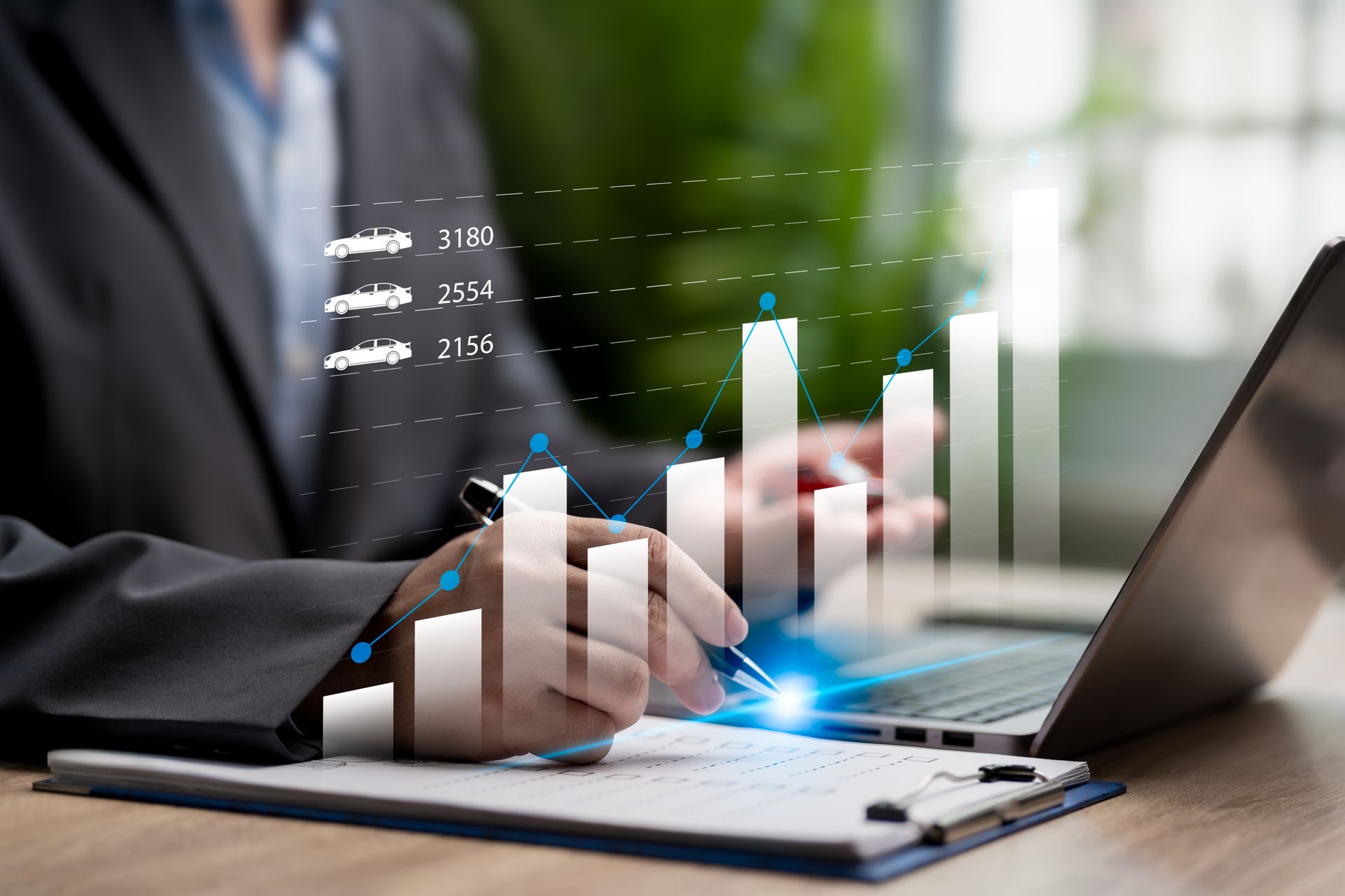 Person in suit analyzing data on laptop with chart overlay.