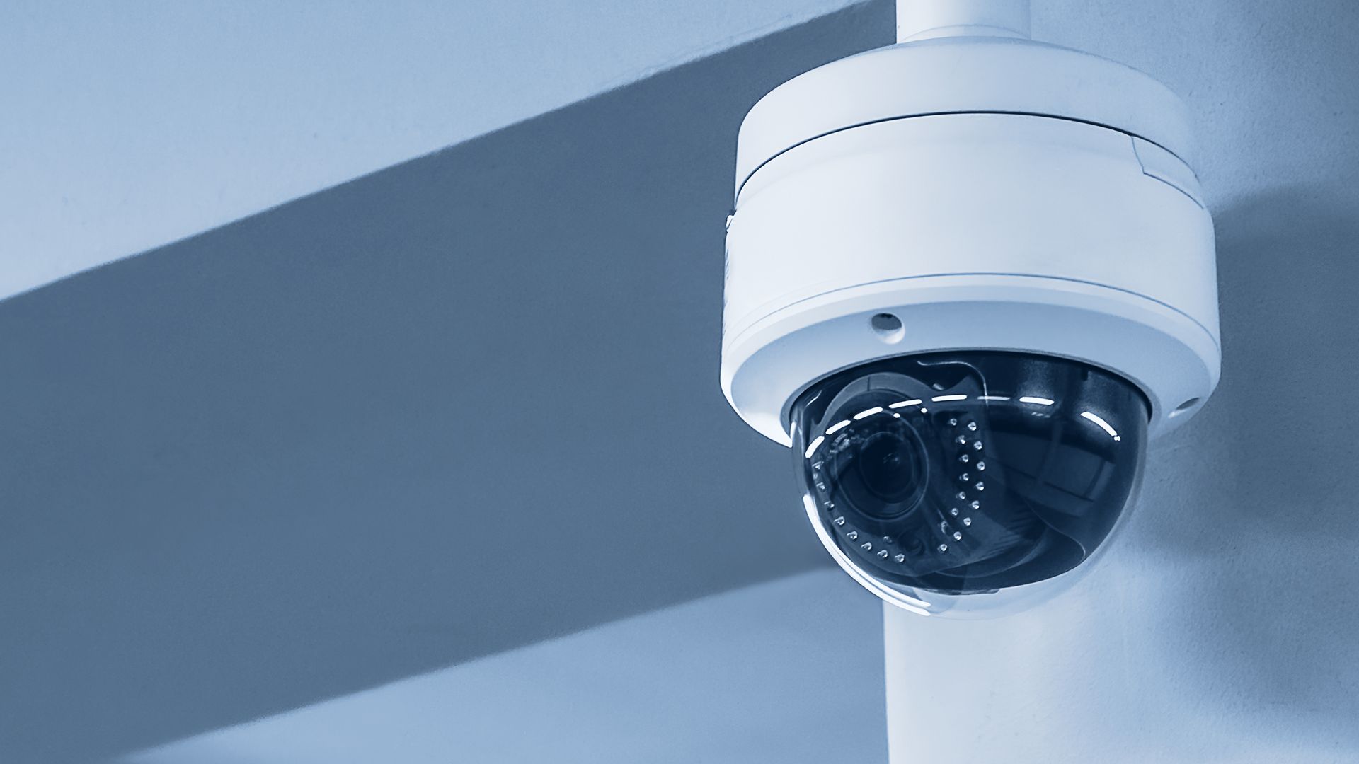 White security camera mounted on a ceiling, capturing surveillance footage.