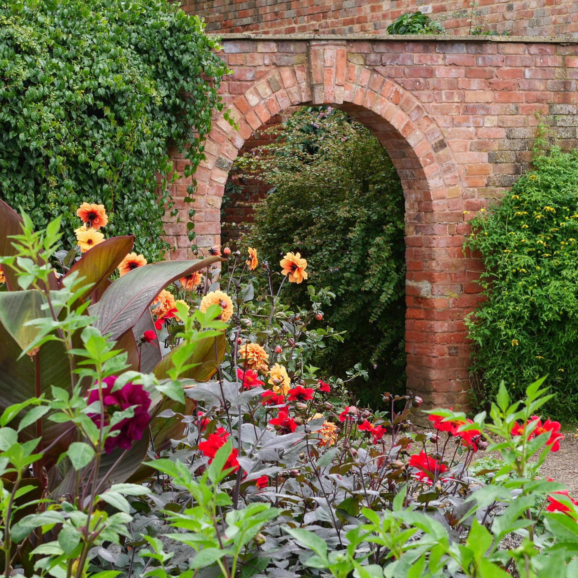 A brick archway is surrounded by flowers and plants