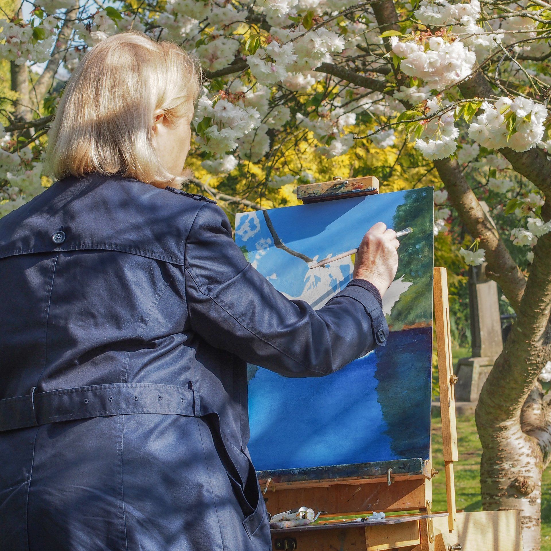 A woman is painting a picture on an easel outside