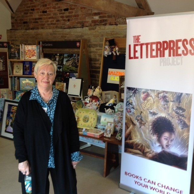 A woman stands in front of a sign that says the letterpress project