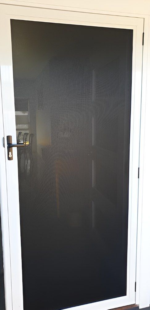 A Black Screen Door With a White Frame is Sitting in a Room — North Coast Screens & Repairs in Ballina, NSW