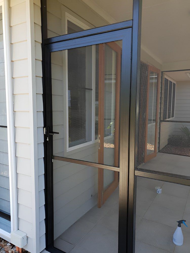 A Screen Door is Sitting on the Side of a House Next to a Window — North Coast Screens & Repairs in Ballina, NSW