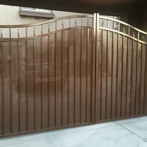 Brown wrought iron gate with curved metal top rail in a garage or driveway entrance