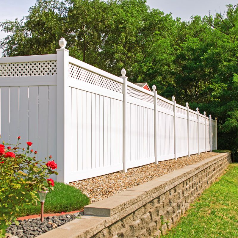 White vinyl privacy fence with greenery behind it