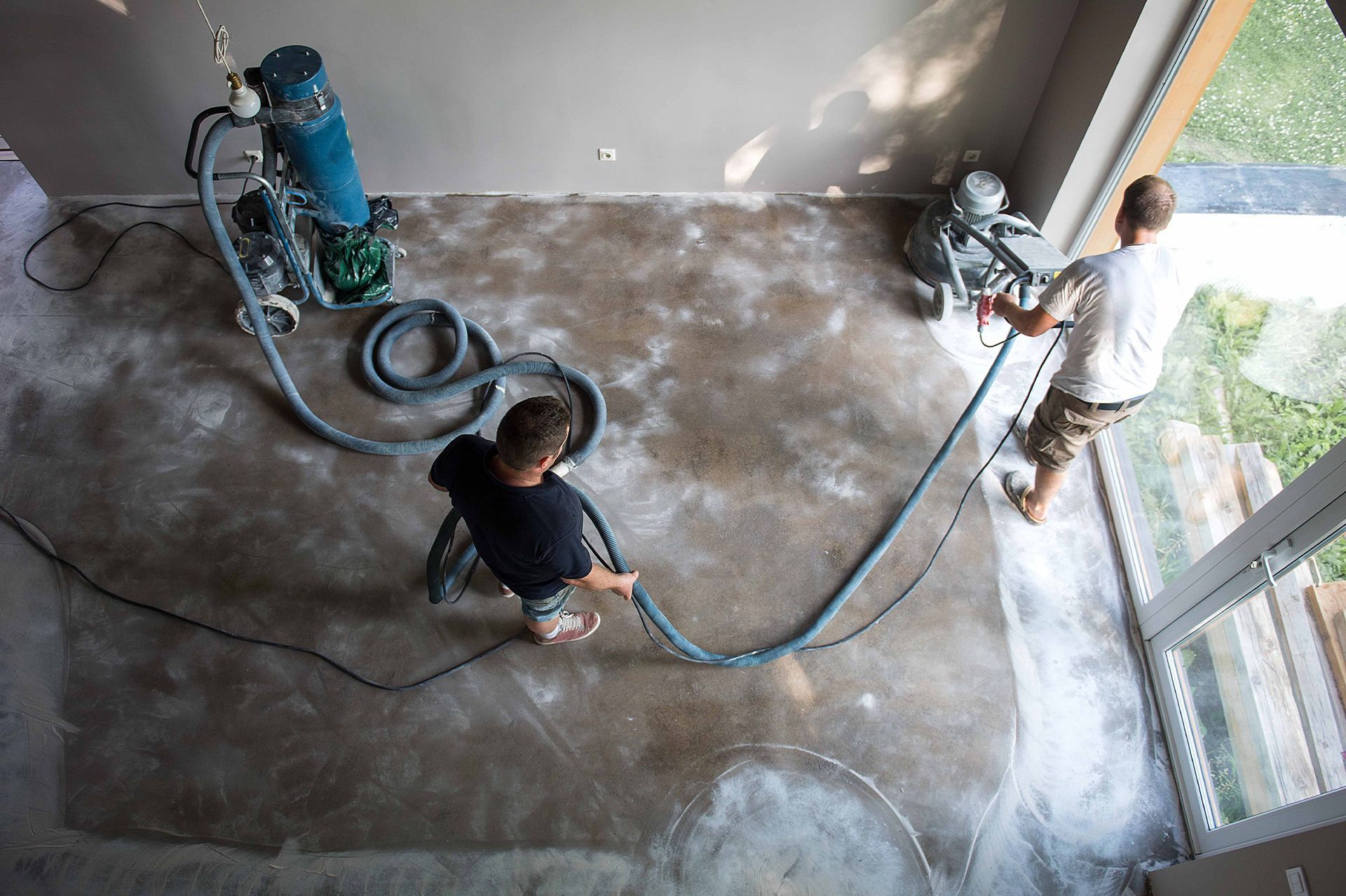 Two vacuum cleaners are sitting next to each other on a tiled floor.