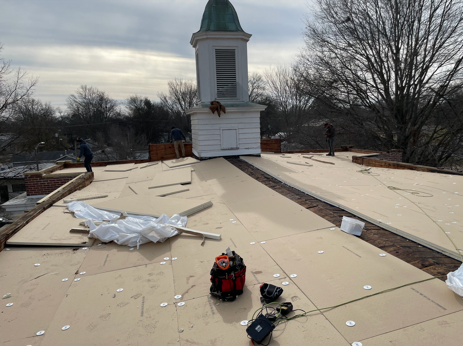 Damaged rooftop with scattered debris and a small tower under cloudy skies