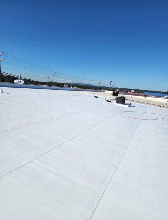 White flat rooftop under a clear blue sky with vents and distant landscape