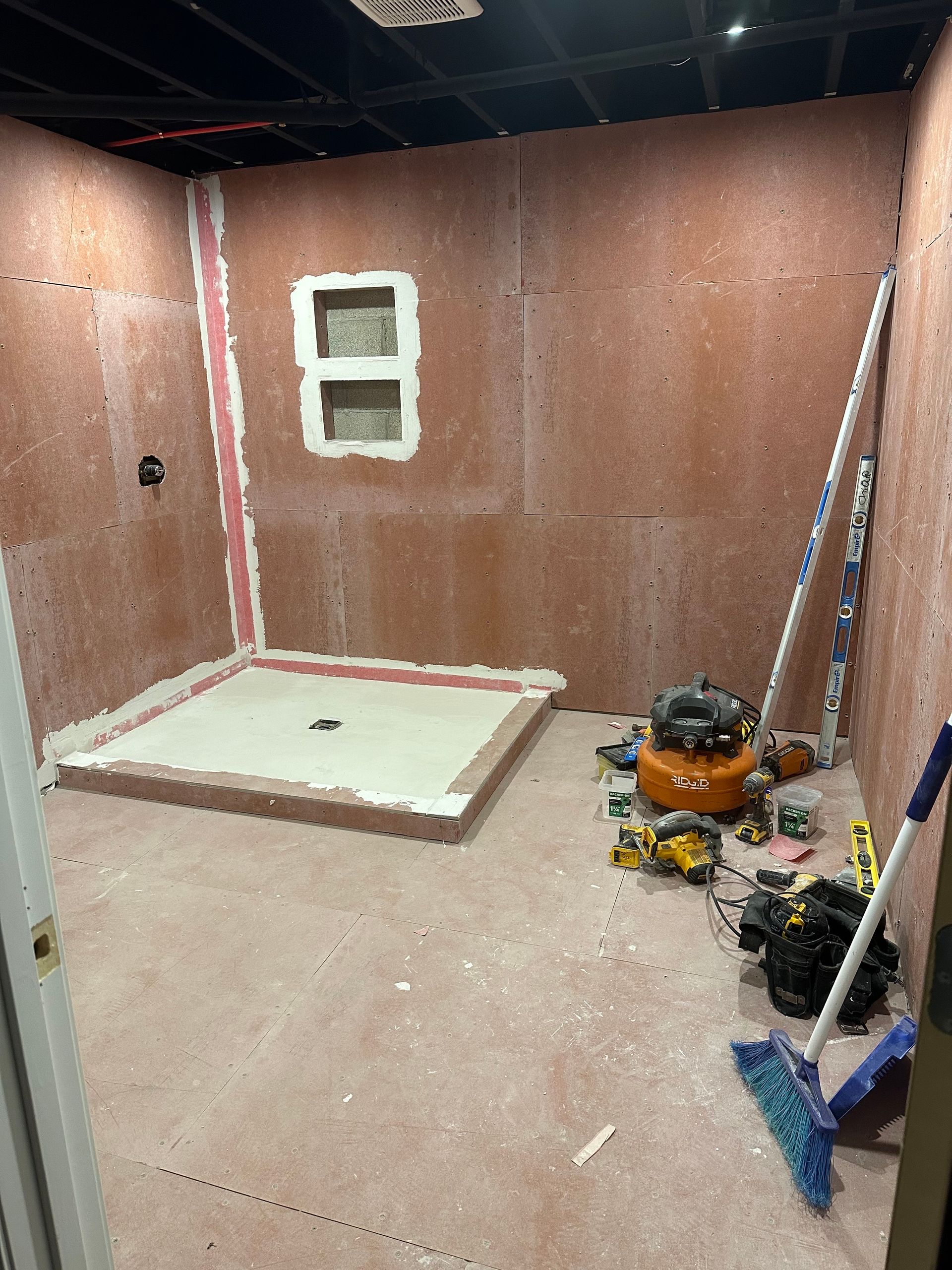 Partially renovated room with exposed walls, a window opening, and tools on the floor