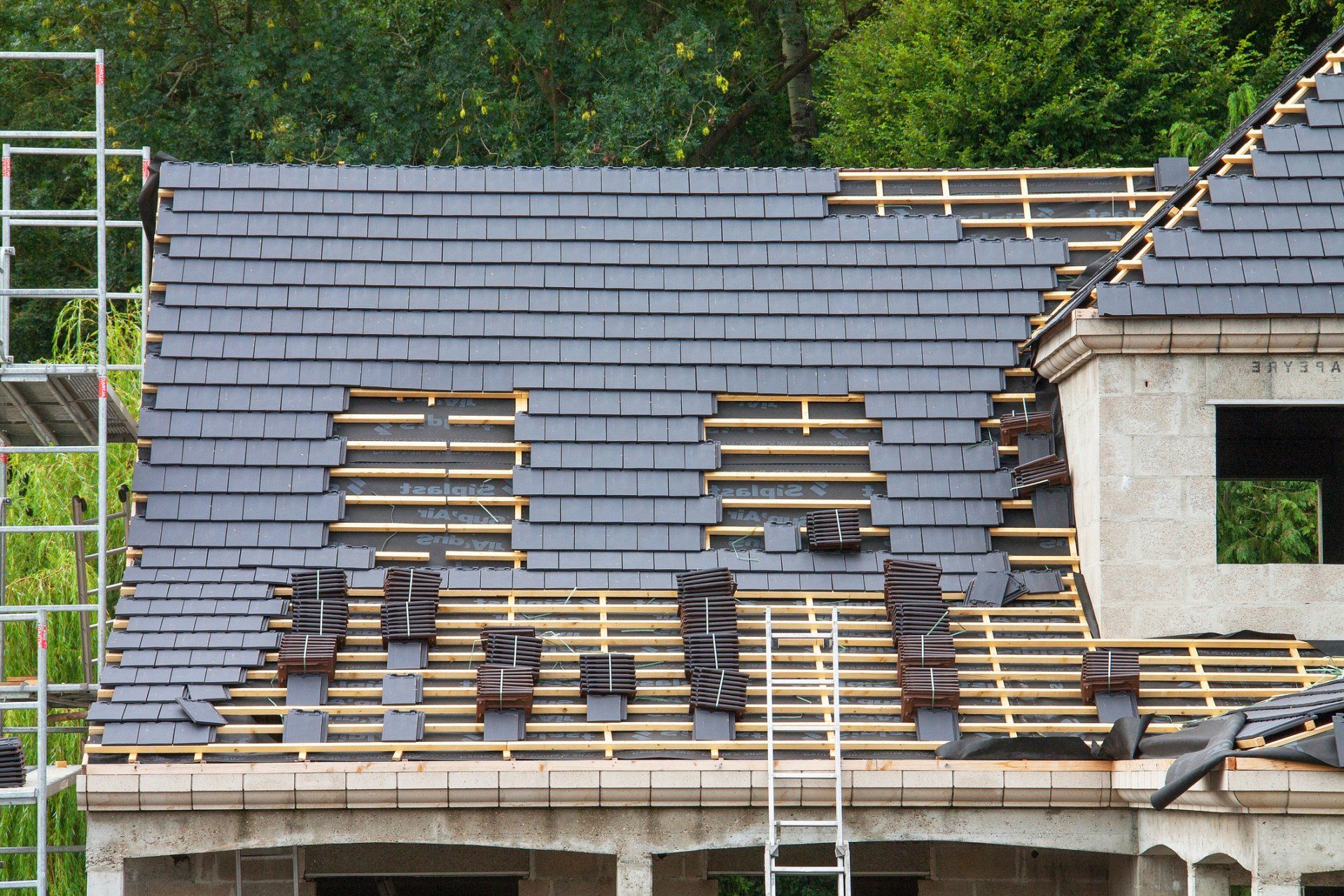 Partially roofed house under construction with exposed wooden battens and scaffolding