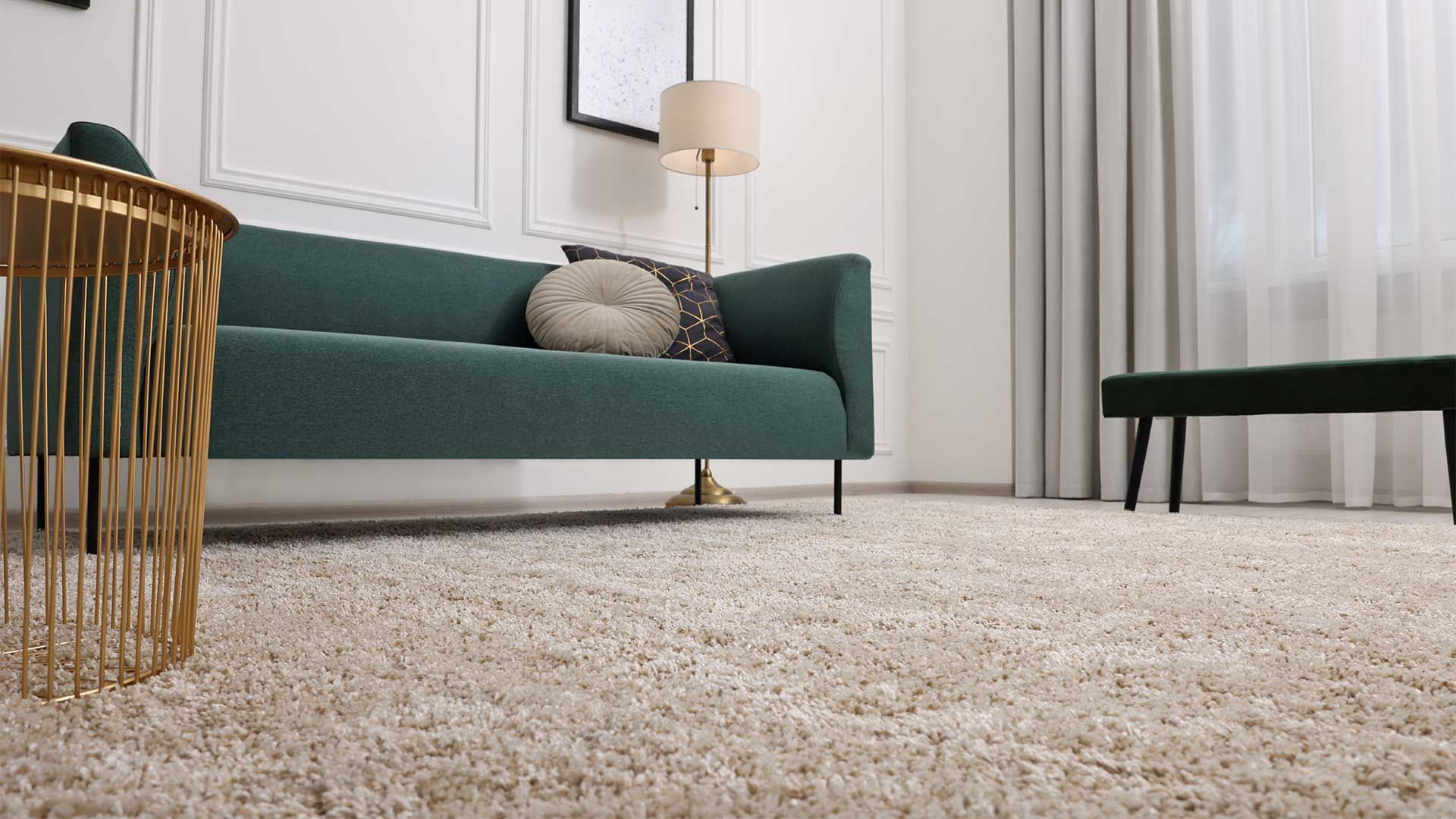 A living room with a green couch and a white rug.