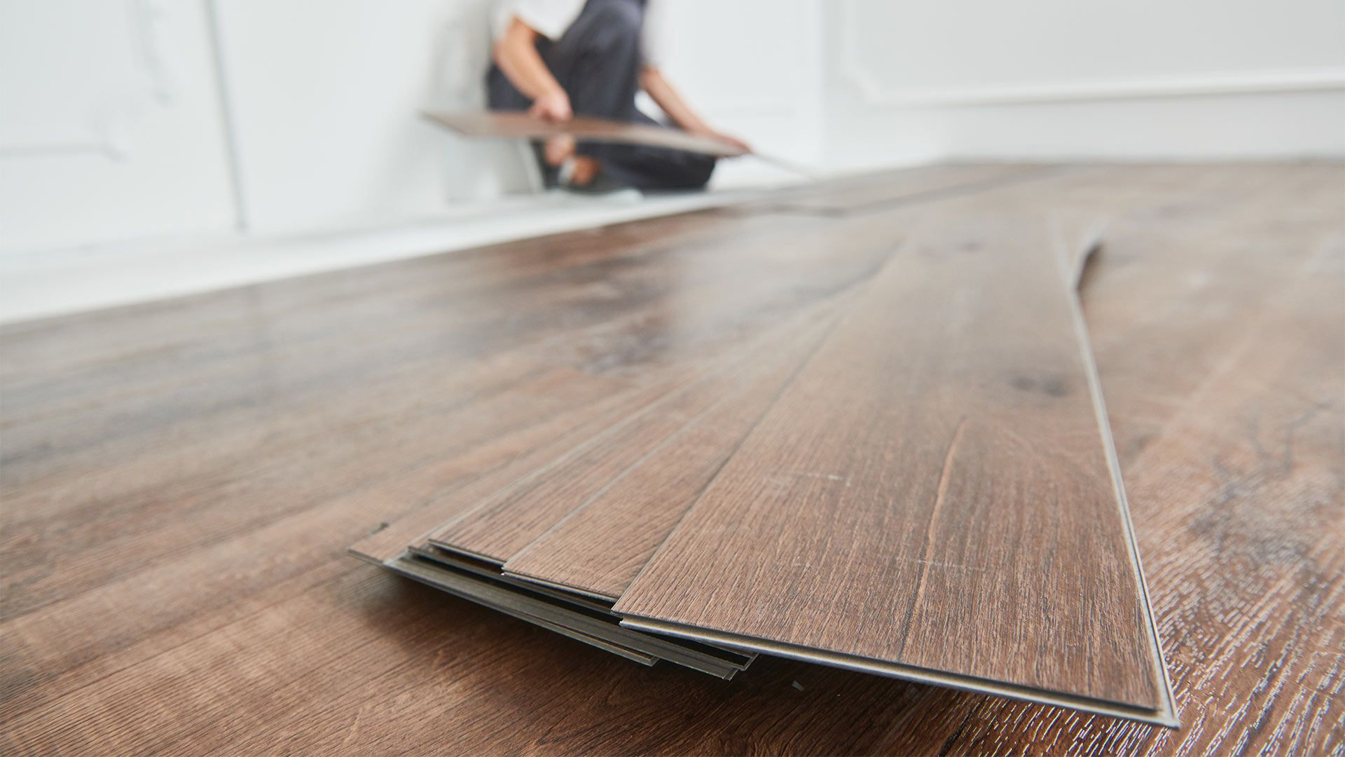 A person is installing a wooden floor in a room.