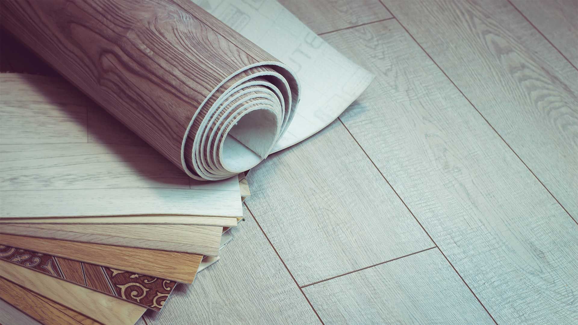 A roll of vinyl flooring is sitting on top of a wooden floor.