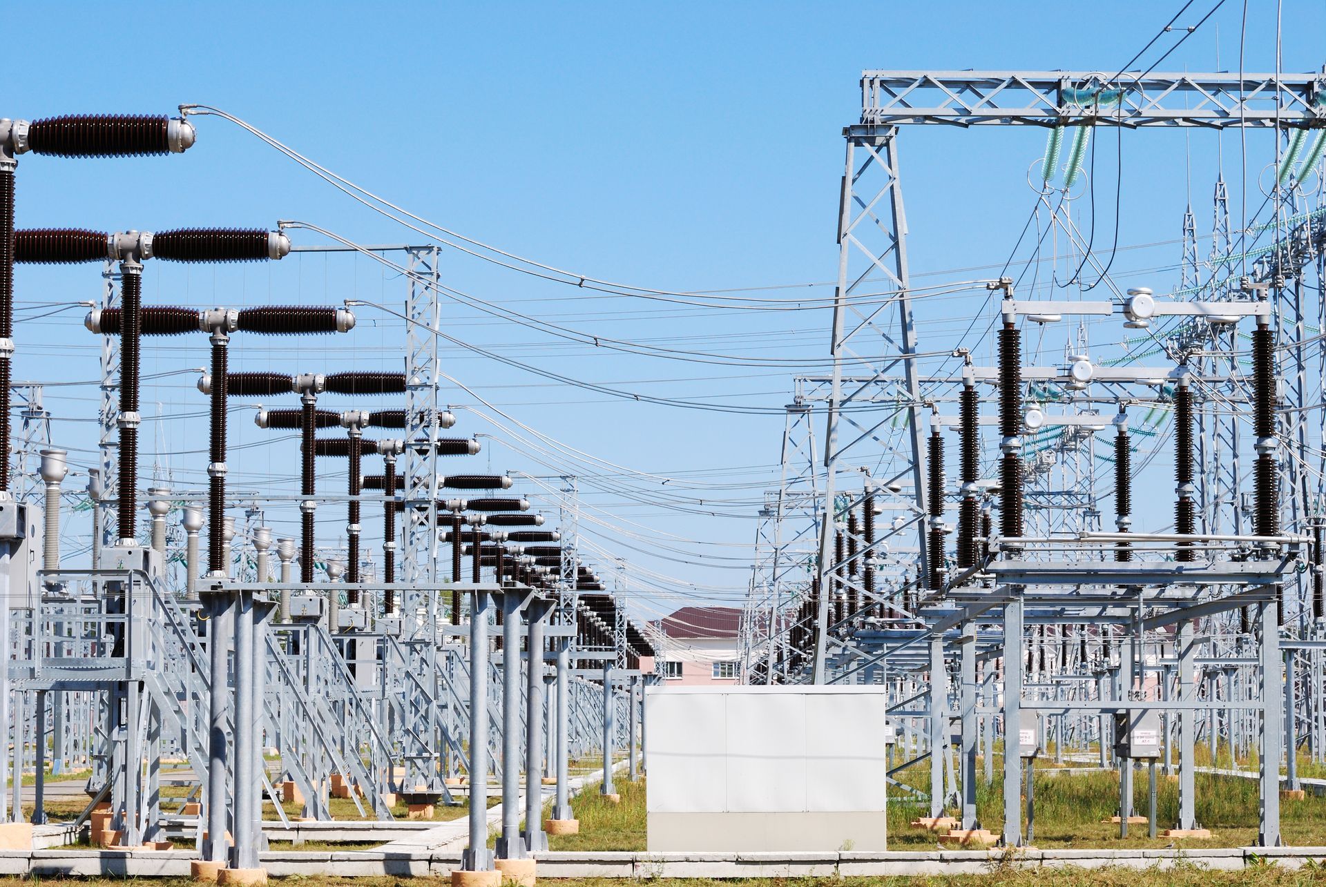 a row of power lines in a field with a blue sky in the background -- representing voltage dip voltage sag