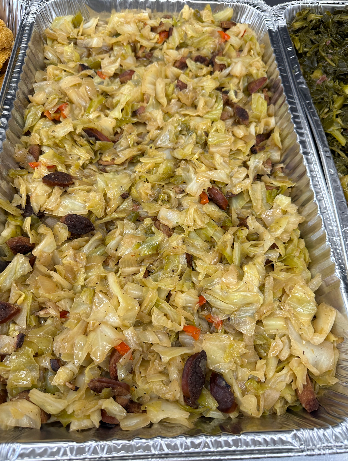 There is a tray of food with cabbage and beans in it.