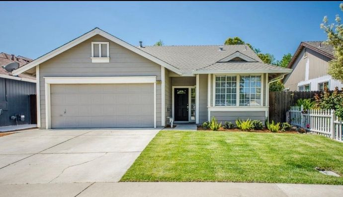 Single-story suburban house with two-car garage, small front lawn, and a concrete driveway