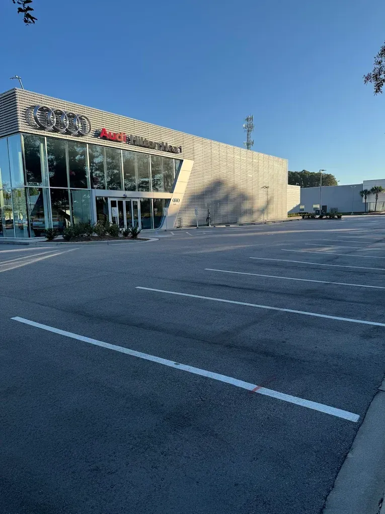 Empty parking lot in front of a glass-fronted Best Buy store on a sunny day