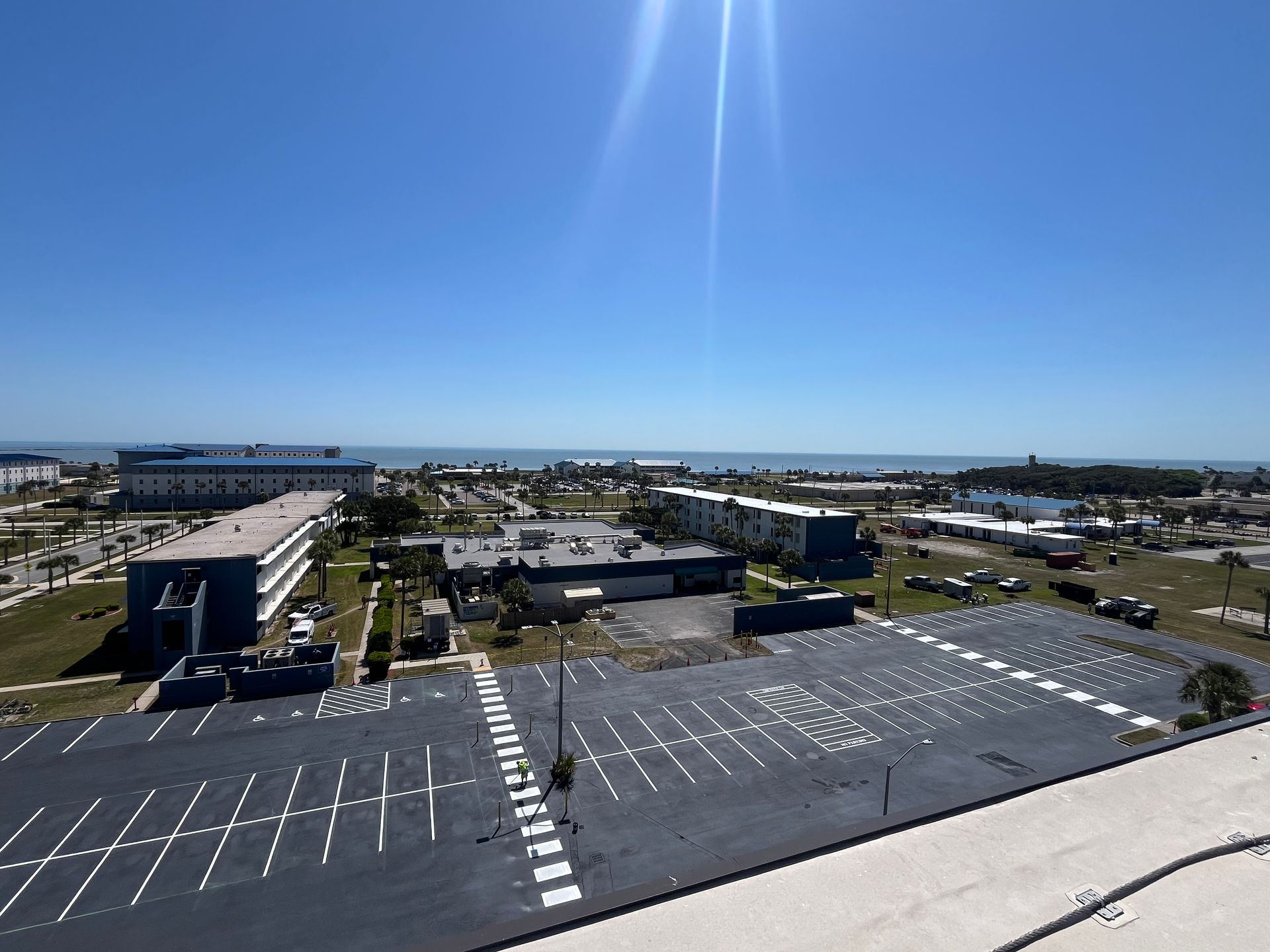 An empty asphalt parking lot with bright yellow painted lines marking individual parking spaces and driving lanes.