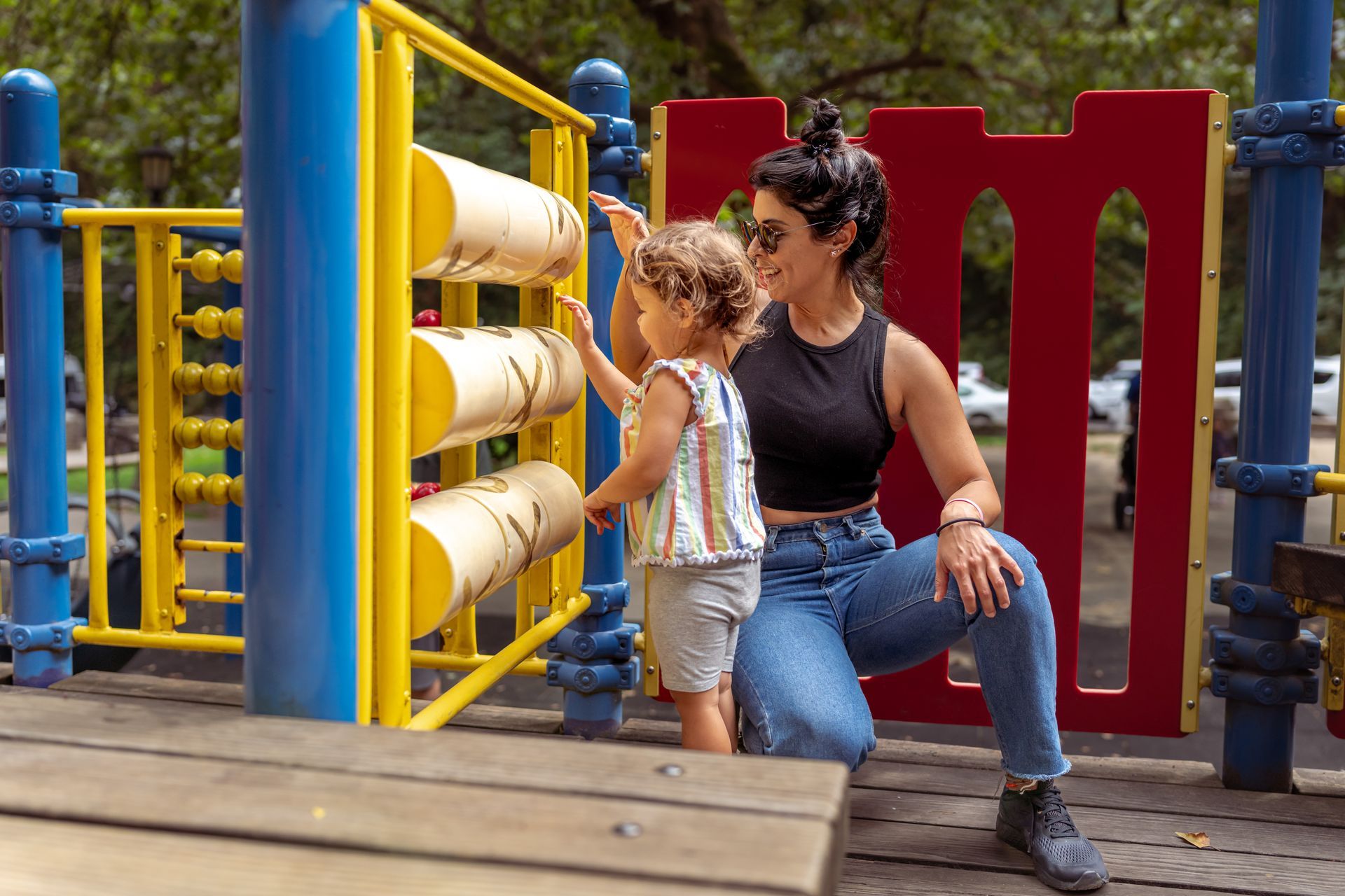 Woman and child playing with a toy at a playground.