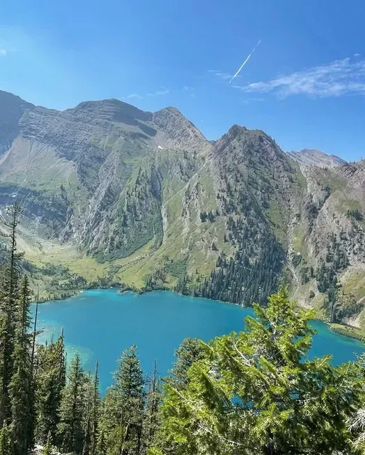 There is a lake in the middle of a mountain surrounded by trees.