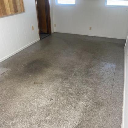 A concrete floor in a room with white walls and a doorway.