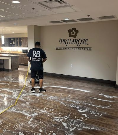 Worker cleaning a vacant office lobby with a Primrose Schools logo on the wall