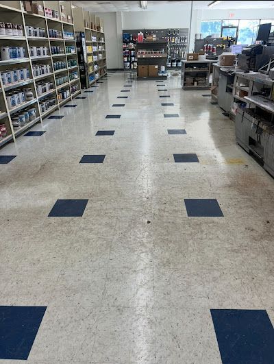 Store interior with shelves of goods, a checkered floor, and a central aisle.