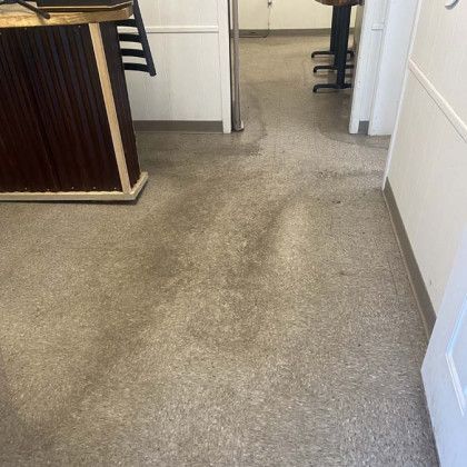 View of a gray floor in a hallway. A dark brown counter and white walls are on either side.
