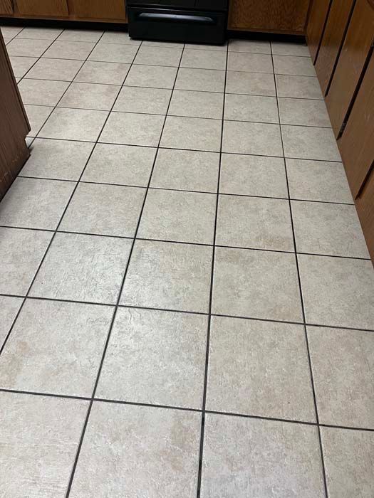 Beige tiled kitchen floor with dark grout lines.