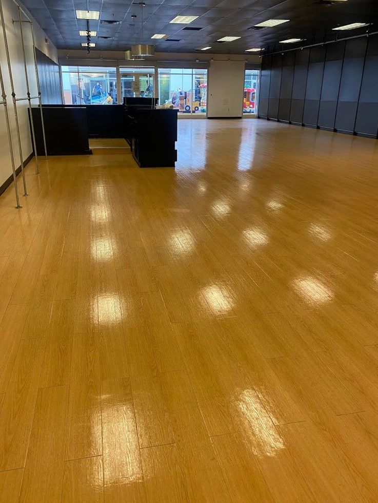 Empty retail space with glossy wood floors and a dark counter.