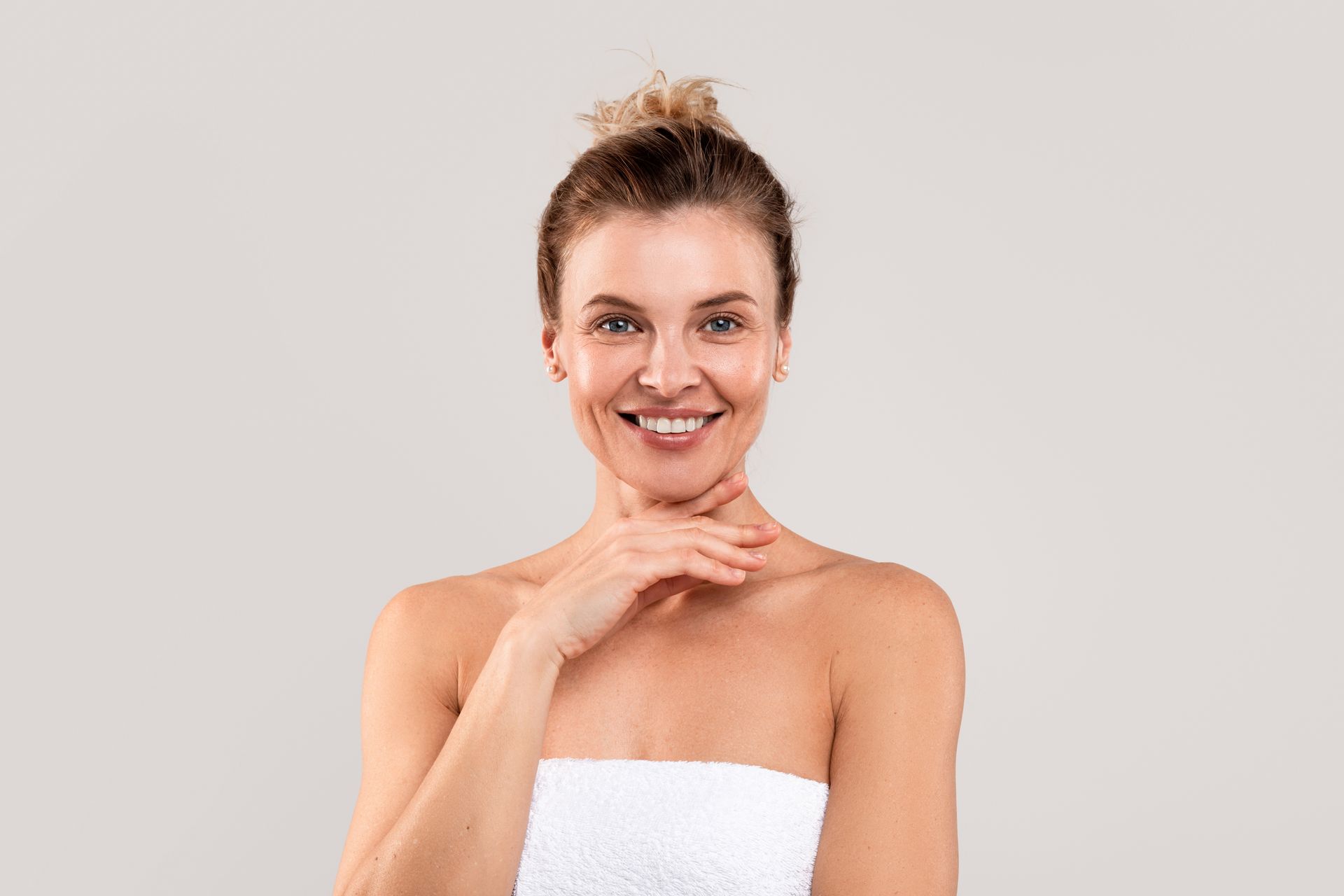 Smiling woman in a white tank top standing indoors in a bright room