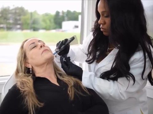 Cosmetologist applying makeup to a reclining client in a bright salon setting