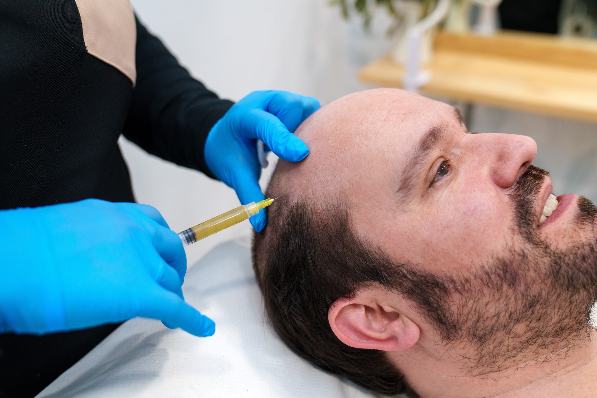 Gloved clinician injecting a man’s forehead with a syringe in a clinical setting