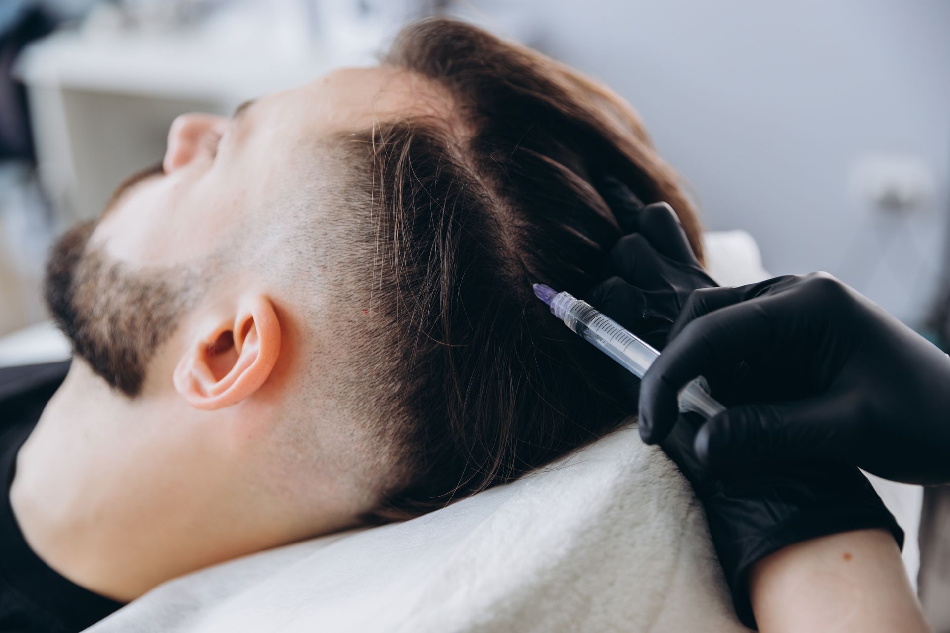 Hair dye being applied to a client’s dark hair at a salon sink