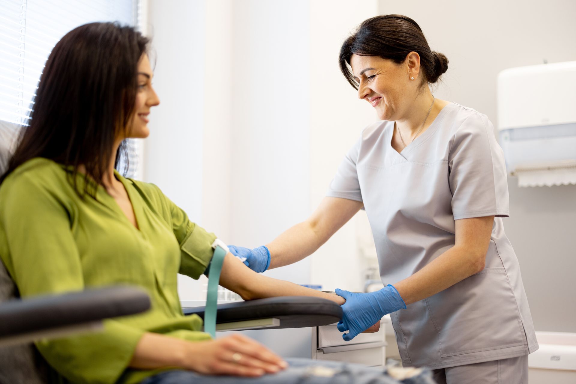 Healthcare worker in gloves taking a woman’s blood pressure in a clinic