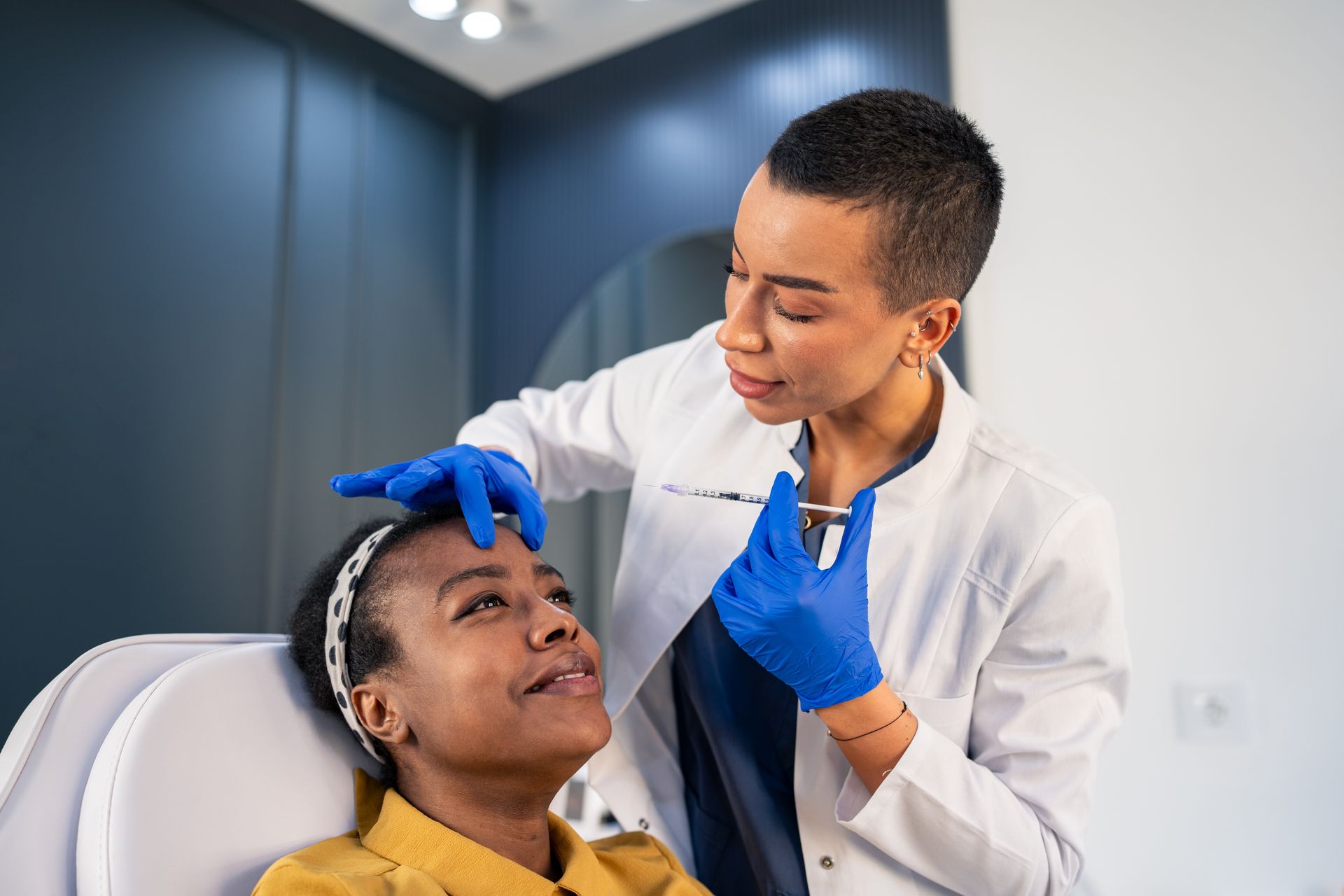 Dentist applying treatment to a patient in a dental chair, wearing blue gloves in a modern clinic.