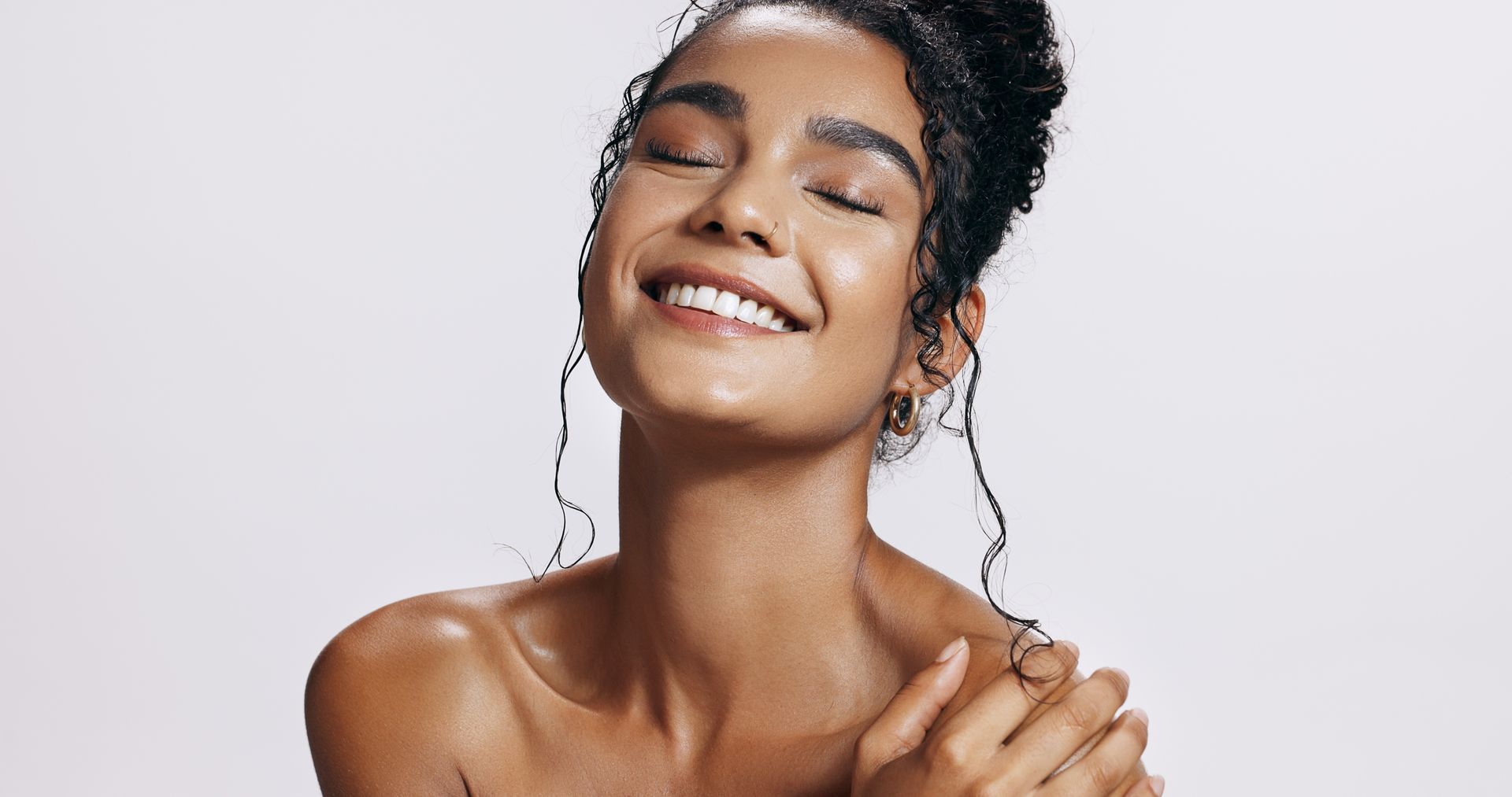 Smiling person with wet hair and bare shoulders against a light background