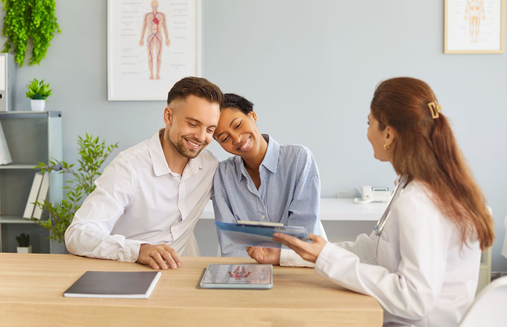 Three people review a tablet in a bright office meeting room.