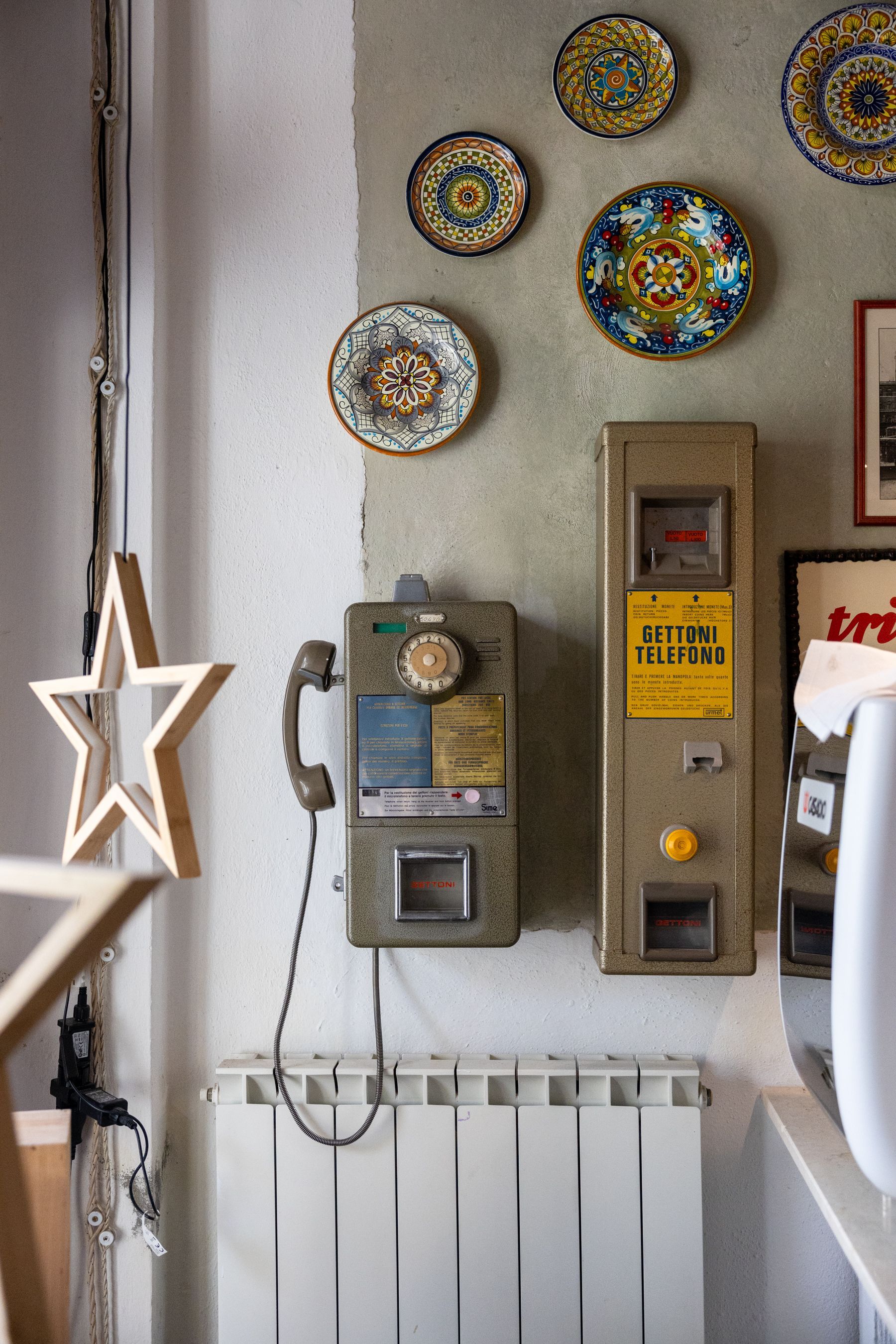 Parete con contatori vintage, piatti decorativi colorati e una stella ornamentale appesa sopra un termosifone.